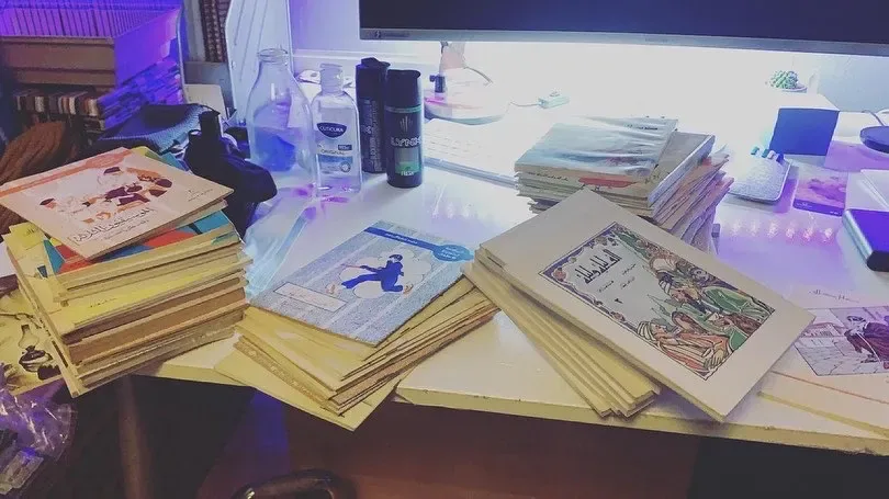 A desk piled with colourful Arabic storybooks